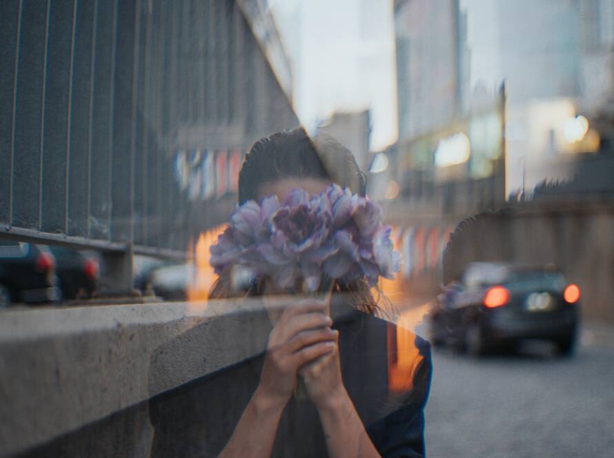 Une femme se cache derrière un bouquet de fleurs